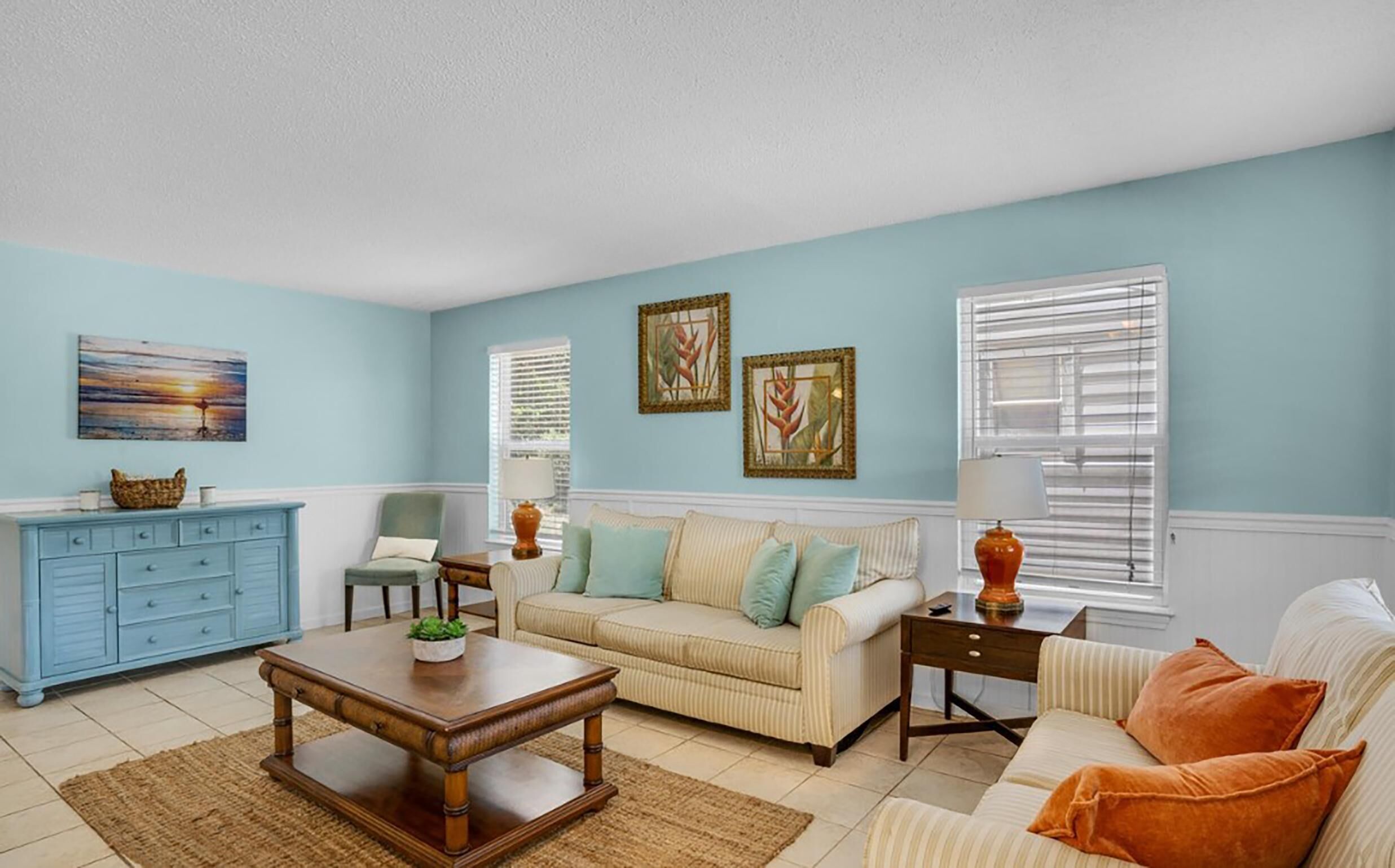 Una sala de estar con pared azul, un sofá color beige, una mesa de centro de madera y un mueble azul.