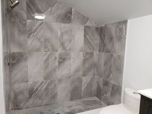 A bathroom with grey marble tiles, a shower, and a toilet. - Country Caledon Charm your private oasis, your home away from home. (Caledon East)