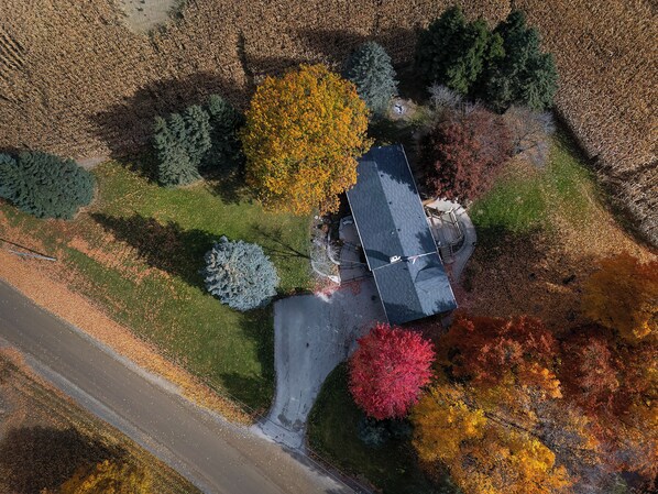 An aerial view of a house surrounded by trees with autumn foliage, a paved driveway, and a small garden area. - Country Caledon Charm your private oasis, your home away from home. (Caledon East)