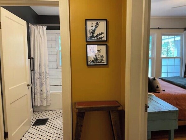 Una habitación con una cama, una mesita y una pared con dos cuadros.