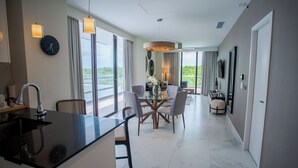 Une chambre d’hôtel moderne dotée d’un coin cuisine, d’une table à manger et d’une grande fenêtre donnant sur un paysage agréable.