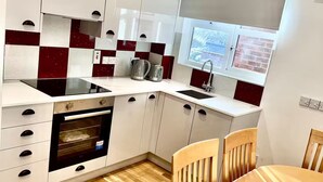 A compact kitchen with white cabinets, a black oven, and a window with a view.