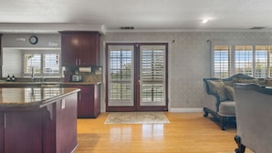 A spacious kitchen with a large island, wooden cabinets, and a double door with glass panels.