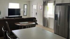 A modern kitchen with a central island, built-in appliances, and a dining area with a sofa and chairs. - Charming 3-bedroom house in Portland (Portland)