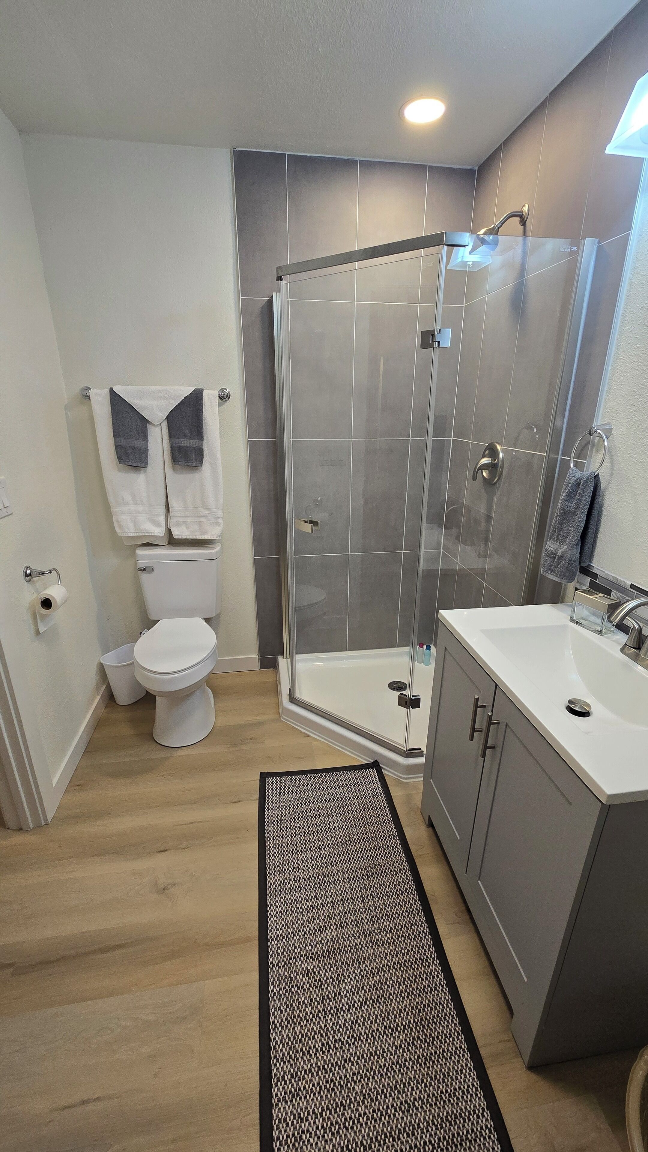 Een moderne badkamer met een douchecabine van glas, een wit toilet en een wastafelmeubel met een wastafel.