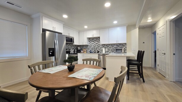 A modern kitchen with white cabinets, stainless steel appliances, and a central island with seating. - Charming 3-bedroom house in Portland (Portland)