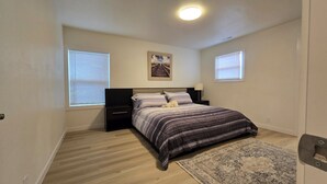 A bedroom with a bed, nightstands, a rug, and two windows with blinds. - Charming 3-bedroom house in Portland (Portland)