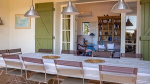 A dining area with a long table, multiple chairs, and pendant lights.