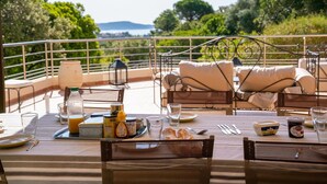 An outdoor dining area with a table set for breakfast, including croissants, juice, and condiments.