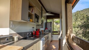 A modern kitchen with a built-in oven, microwave, and sink. There is a window overlooking a garden.