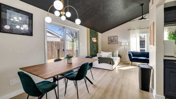 Un interior moderno con comedor, sofá, una silla azul y un ventilador de techo.