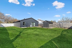 A residential property with a well-maintained lawn, a detached garage, and a shed.