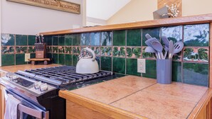 Una cocina con estufa a gas, un hervidor y un juego de utensilios en un organizador.