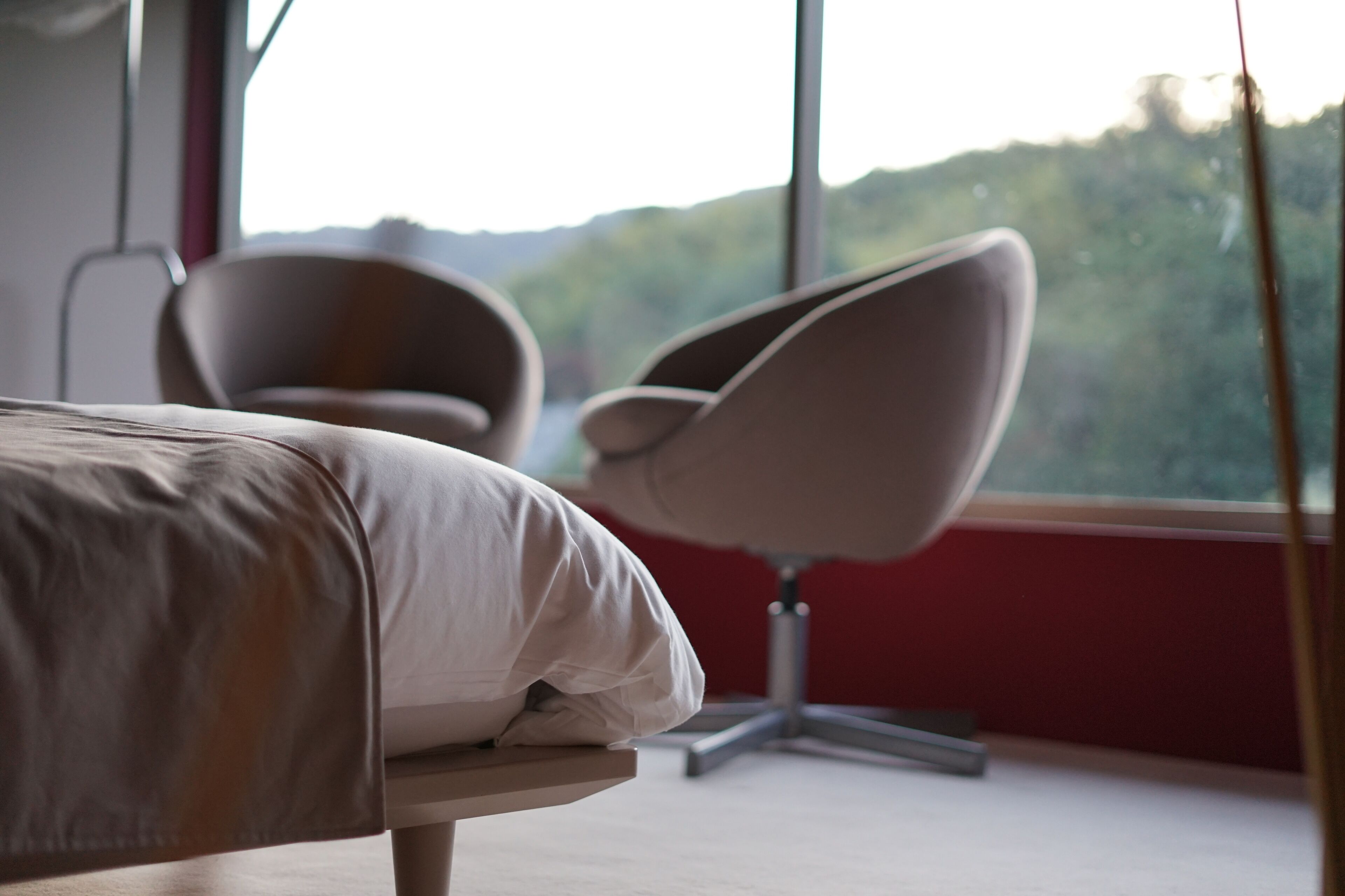 Un dormitorio con cama, una silla y un ventanal que ofrece vistas a zonas verdes.