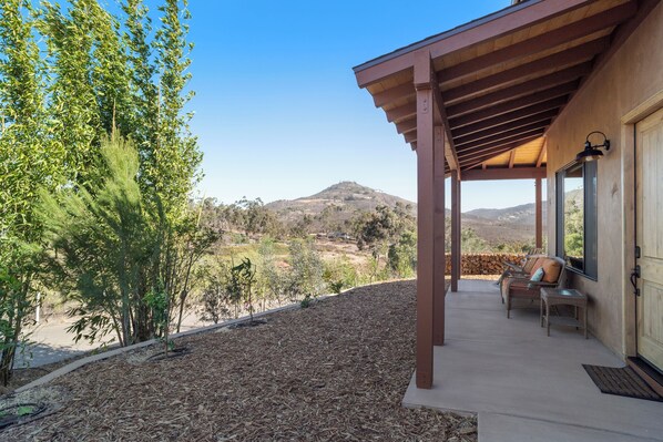 A covered outdoor area with a view of a mountain, wooden pergola, and seating.
