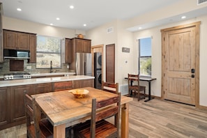 Una cocina con armarios de madera, una isla central y un comedor con mesa y sillas de madera.
