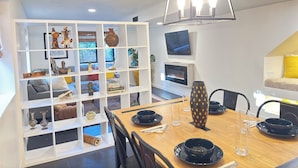 A modern dining area with a wooden table set for two, surrounded by white shelving units with various decorative items. - Rustic luxe Hideaway-near Beautiful American Fork Canyon! (Highland)