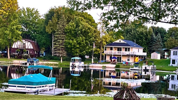 Ein Anwesen am Seeufer mit Anlegesteg, überdachtem Boot und Haus mit Balkon mit Seeblick.