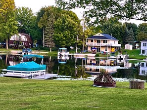 A lakeside property with a dock, a covered boat, and a house with a balcony overlooking the water.