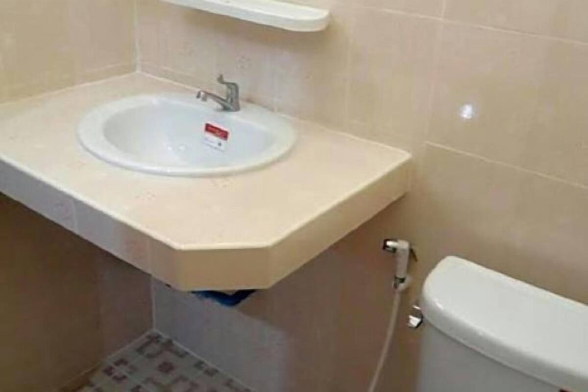 A bathroom with a white sink, a toilet, and a beige countertop.