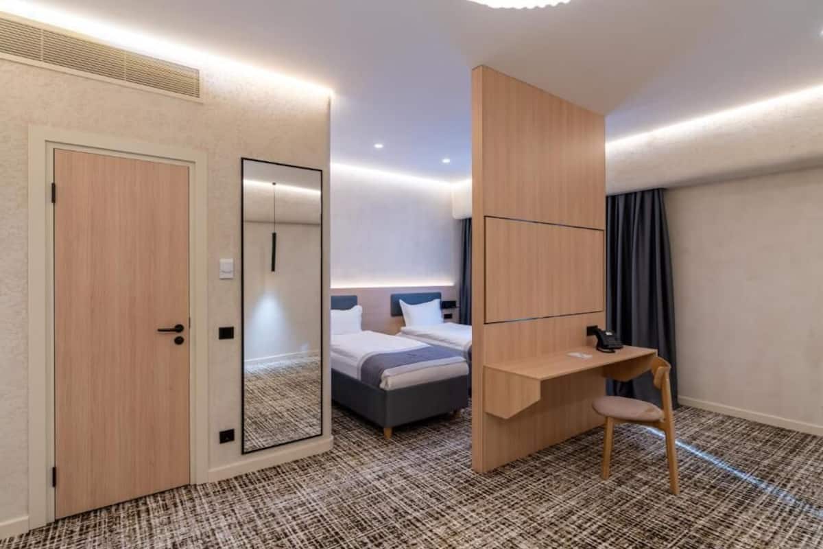 Une chambre d’hôtel comprenant un lit, un bureau avec une chaise, un miroir et une armoire.