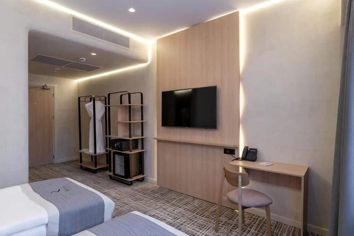Une chambre d’hôtel moderne équipée d’un lit, d’un bureau, d’une télévision et d’une armoire.