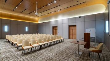 A conference room with rows of chairs, a podium, and a carpeted floor.