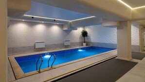 Una piscina con bordo piastrellato, una pianta in vaso e un termosifone bianco a parete.