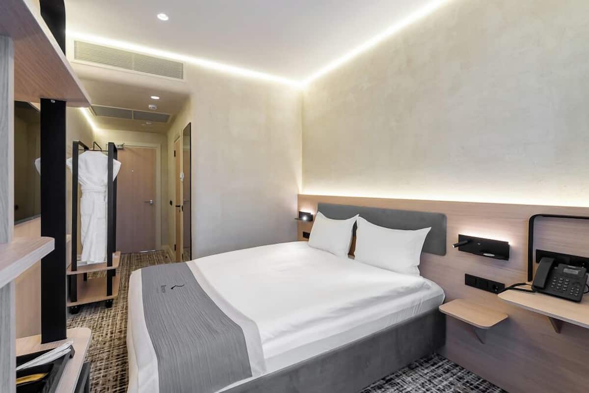 Une chambre d’hôtel moderne avec un grand lit, une table de chevet et une armoire.