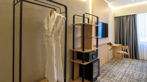 Una camera d'albergo con un letto, una televisione, una scrivania, una sedia e un armadio.