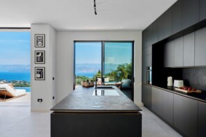 Una cucina moderna con un'ampia isola, mobili scuri e vista sul mare.