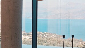 A dining area with a large window overlooking a coastal landscape. - Luxury Villa with Infinity Pool & Sea Views in Northeast Corfu (kassiopi)