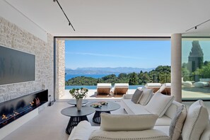 Un salon moderne doté d’une cheminée, de sièges confortables et d’une grande fenêtre offrant une vue panoramique.