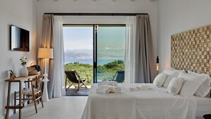 A bedroom with a bed, a desk, a chair, a TV, and a view of the outdoors. - Luxury Villa with Infinity Pool & Sea Views in Northeast Corfu (kassiopi)