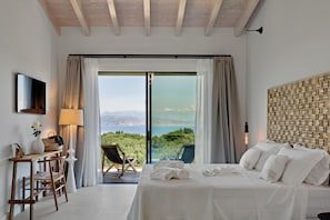 Une chambre à coucher avec un lit, un bureau, une chaise, un téléviseur et une vue sur l’extérieur.