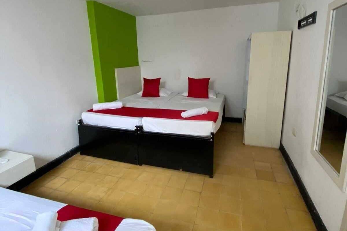 A hotel room with two beds, a wardrobe, and a mirror.