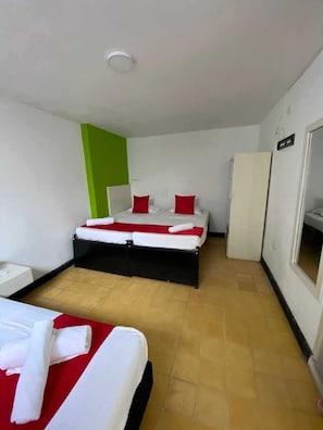 A hotel room with two beds, a wardrobe, and a mirror.