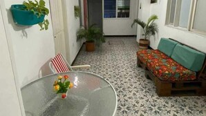 A small, tiled room with a round glass table, a sofa, and potted plants. - Believer Hostel (Santa Marta)