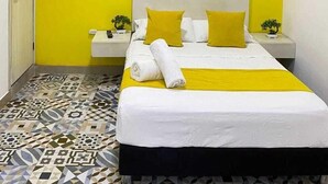 A hotel room with a bed, a nightstand, a wall-mounted air conditioner, and a patterned floor. - Believer Hostel (Santa Marta)