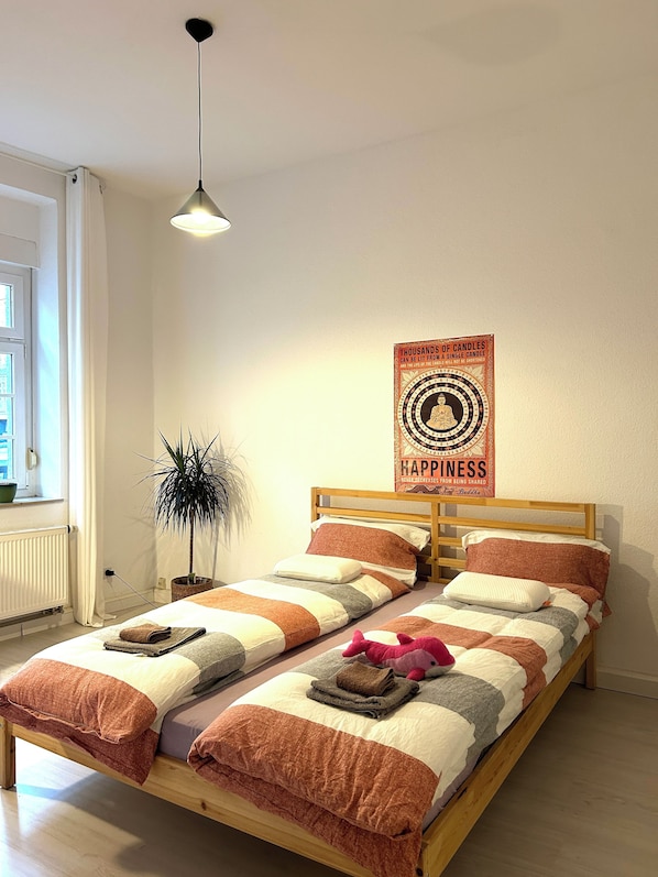 Een bed met houten frame, gestreept beddengoed en een poster aan de muur.