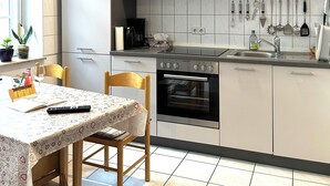 A modern kitchen with a built-in oven, a coffee maker, and various utensils hanging on the wall. - Apartment, 10 min. walk to the center, 45m2,Netflix& all amenities! (Erfurt)