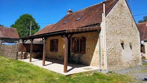 A stone house with a sloped roof, wooden beams, and a small porch.