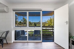 A room with a large sliding glass door leading to an outdoor area with a view of greenery and a fence. - Gateway Retreat Near Flinders Uni & Hospital (Bedford Park)