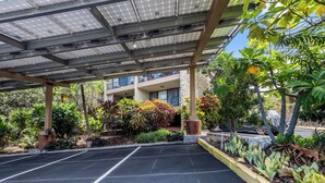 A parking area with marked spaces, a covered walkway, and a building with balconies. - Kalanikai 118 Highly Walkable! (Kailua-Kona)