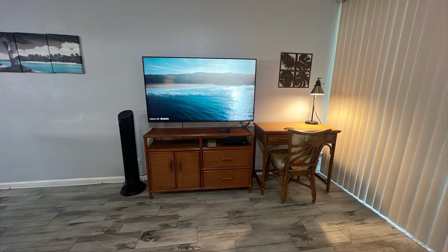 Ein Wohnzimmer mit Flachbildfernseher, Holzschrank und Schreibtisch mit Stuhl.