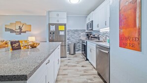 A modern kitchen with white cabinets, stainless steel appliances, and a granite countertop. - Kalanikai 118 Highly Walkable! (Kailua-Kona)