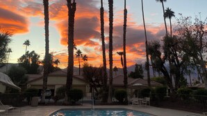 A swimming pool with palm trees and a sunset sky. - Luxury 2BR/2BA Smart Home in Monterey Country Club – Palm Desert, CA (Palm Desert)