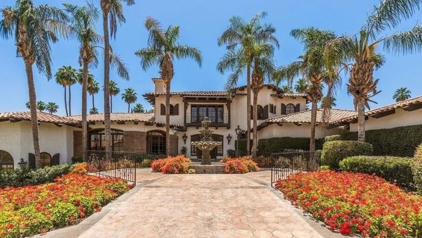 A Mediterranean-style building with a central courtyard, palm trees, and a fountain. - Luxury 2BR/2BA Smart Home in Monterey Country Club – Palm Desert, CA (Palm Desert)