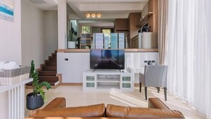 Una sala de estar moderna con televisor, sofá y comedor.