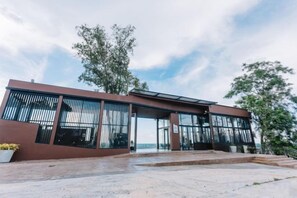 A modern building with large windows and a flat roof, surrounded by trees. - Sky Hill Villa Surattthani (Surat Thani)